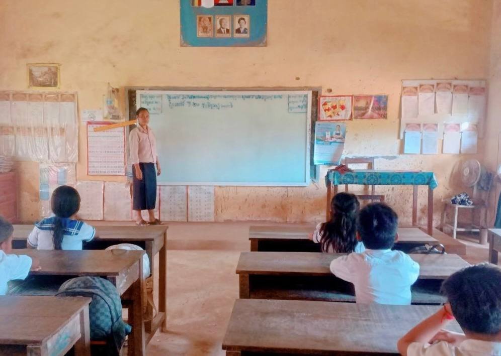 A Grade 2 primary school teacher standing at the front of a classroom teaching her students.