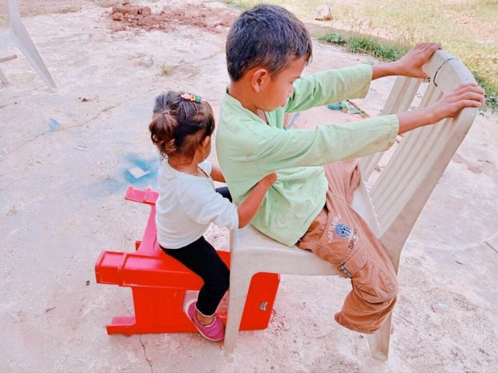 Boy and girl sitting tandem on two plastic chairs pretending to ride a train.