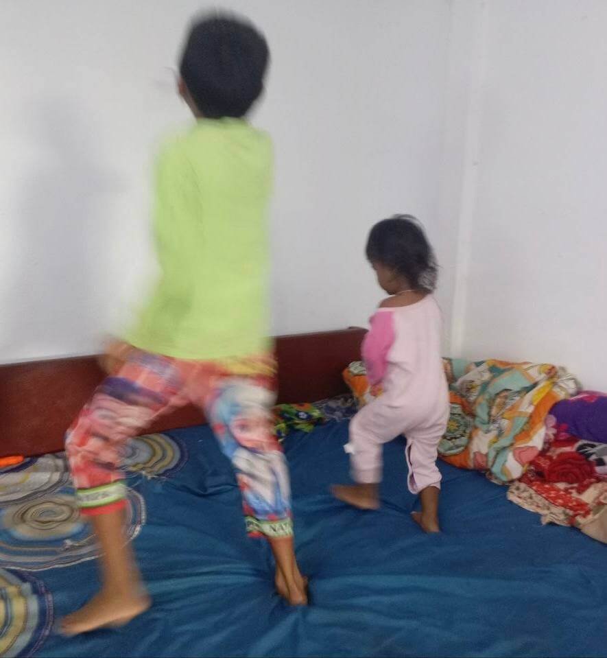Two children freestyle dancing on a bed with motion blur demonstrating energetic movement.