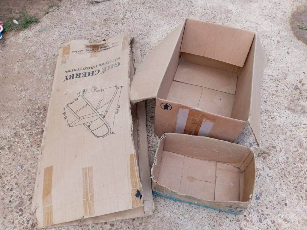 Three empty cardboard boxes of different sizes sitting on a concrete path ready for a DIY project.